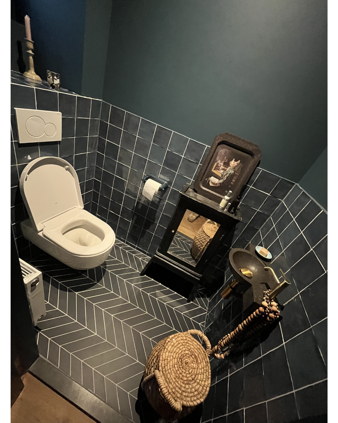 Stijlvolle toiletruimte met donkere tegels en visgraat vloer